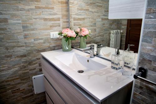 a bathroom with a sink with flowers in vases on it at Casa Fedele in LʼAquila
