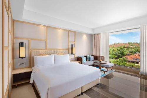 a bedroom with a large white bed and a large window at The Westin Goa in Vagator