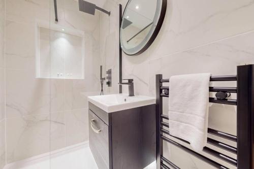 a white bathroom with a sink and a mirror at Stunning 3BD flat in Kilburn with an outdoor area in London