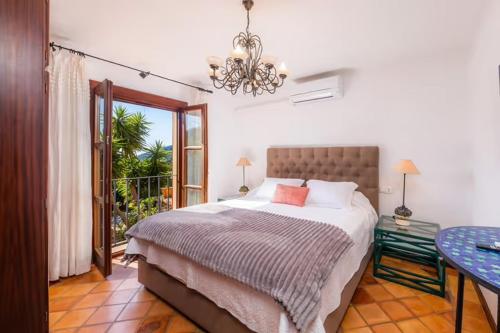 a bedroom with a bed and a chandelier at Villa Can Nofre, con un magnífico jardín y espectacular piscina in Capdepera