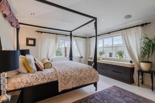 ein Schlafzimmer mit einem Himmelbett und einem Fenster in der Unterkunft Milestone in Winchcombe