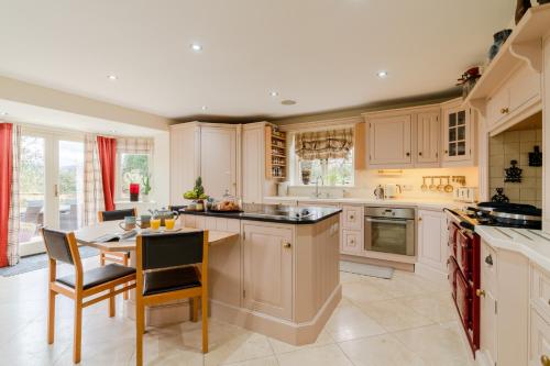 a kitchen with white cabinets and a table and chairs at Milestone in Winchcombe