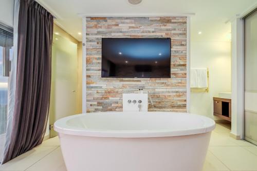 a bath tub in a bathroom with a tv on a brick wall at Malibu in Cape Town