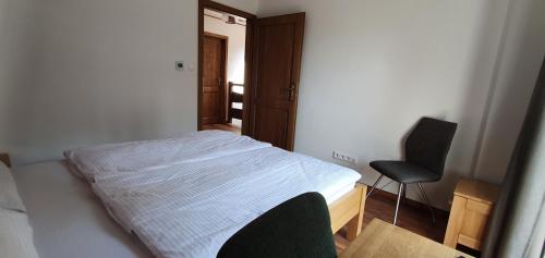 a small bedroom with a bed and a chair at Chata Krpko in Horná Lehota