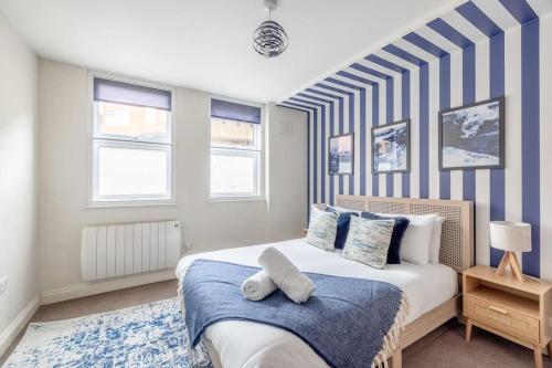 een slaapkamer met een bed met een blauwe en witte streepmuur bij Central Windsor 1BR Gem in Windsor