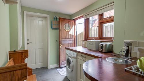 a kitchen with a washer and dryer in it at Palmer's Cottage in Southwold