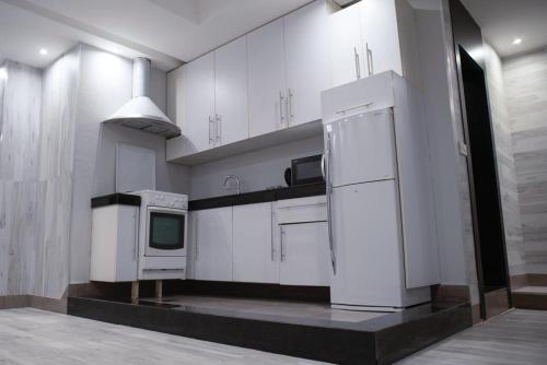 cocina con armarios blancos y nevera blanca en Terrace Furnished Apartments Fintas 2, en Kuwait