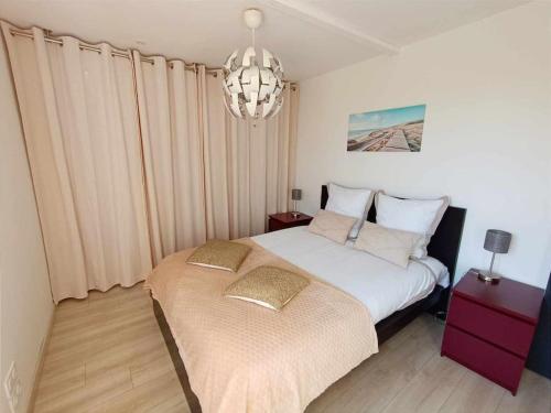Un dormitorio con una cama y una lámpara de araña. en Maison l'Escale du port, en Berville-sur-Mer