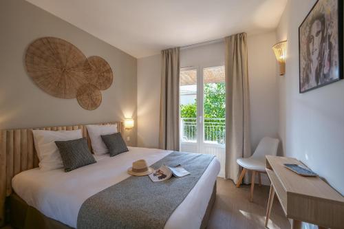 una camera d'albergo con un letto con un cappello sopra di St Tropez et plage à pied Escale de Charme - 3 a Saint-Tropez