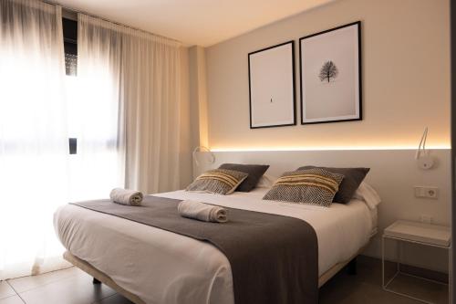 um quarto com uma cama grande e 2 almofadas em Apartamentos Turísticos Puerta Real em Cartagena