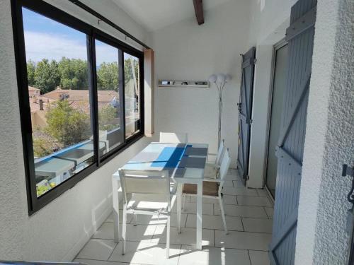 un balcon avec une table, des chaises et une fenêtre dans l'établissement St Cyprien Joli T3 avec vue sur la lagune, à Saint-Cyprien