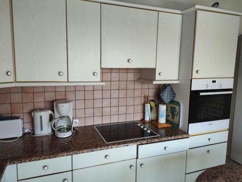 une cuisine avec des armoires blanches et un comptoir dans l'établissement St Cyprien Joli T3 avec vue sur la lagune, à Saint-Cyprien