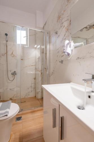 a white bathroom with a shower and a sink at Tinas Village Free Transport from/to the airport in Spáta