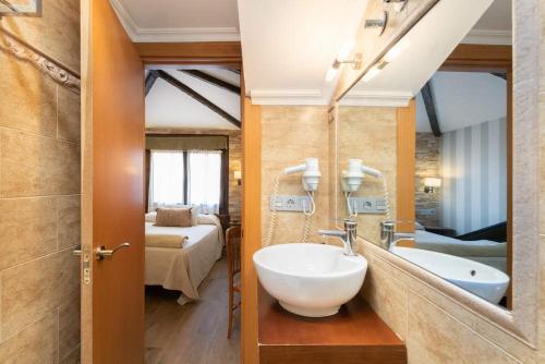 uma casa de banho com um lavatório e um espelho grande em CimaVilla Rooms em Gijón