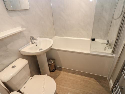 een badkamer met een toilet, een wastafel en een bad bij Foxglove Cottage in Richmond
