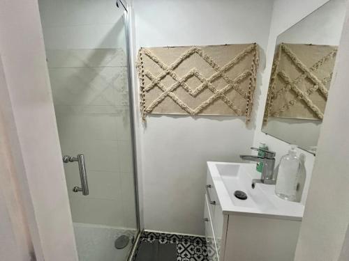 uma casa de banho branca com um chuveiro e um lavatório. em Le cocon des cloutiers - Central & Moyen séjour em Liège