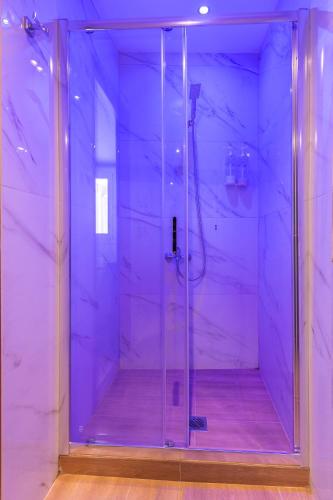 a glass shower in a room with purple lighting at Tinas Village Free Transport from/to the airport in Spáta