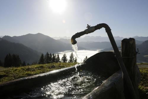 a stream of water pouring from a pipe into a tub at HUBERTUS Mountain Refugio Allgäu in Balderschwang
