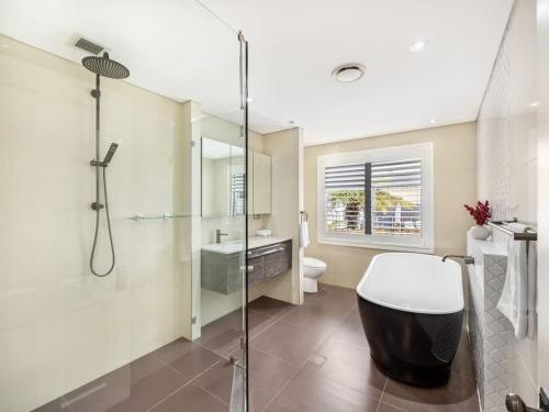 un baño con ducha y bañera en Riverfront Oasis Spacious 5BR Luxury w 10m Pool, en East Hills