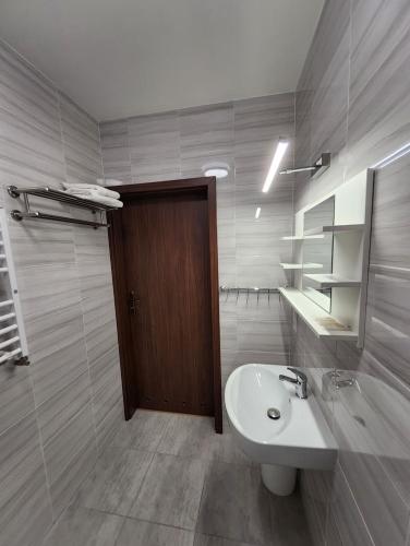 a bathroom with a sink and a toilet and a door at Hotel Resident in Suchedniów