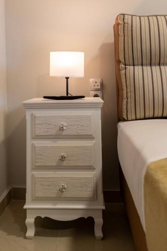 a white dresser with a lamp on it next to a bed at Tinas Village Free Transport from/to the airport in Spáta