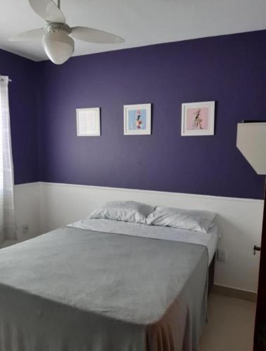 a bedroom with a bed with a purple wall at Serra Mar Suítes,Lofts, e casas à 300 metros das praias in Arraial do Cabo
