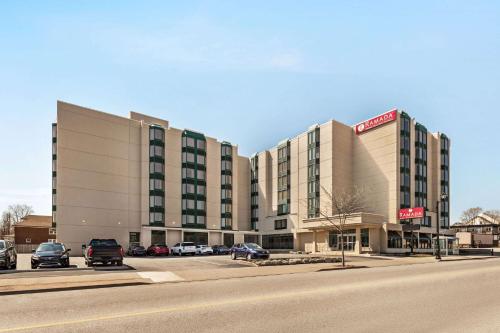 een hotelgebouw met auto's geparkeerd op een parkeerplaats bij Ramada By Wyndham Niagara Falls near the Falls in Niagara Falls