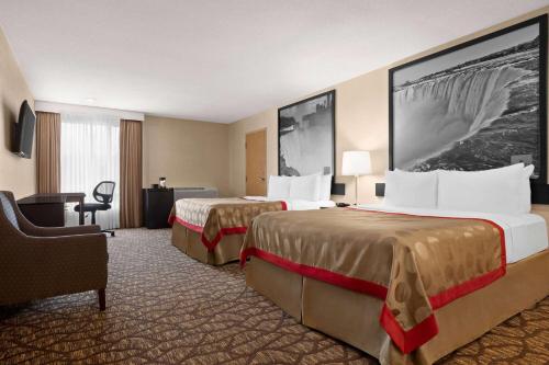 a hotel room with two beds and a desk at Ramada By Wyndham Niagara Falls near the Falls in Niagara Falls
