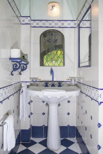 a bathroom with a white sink and blue and white tiles at Hotel Villino Della Flanella in Modena
