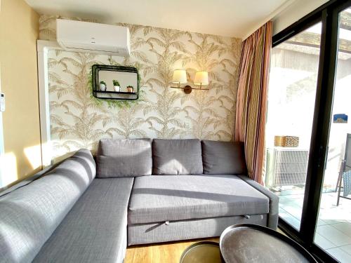 - un canapé dans une pièce avec un mur et un miroir dans l'établissement Le Delacroix By SCLS Locations, à Cannes