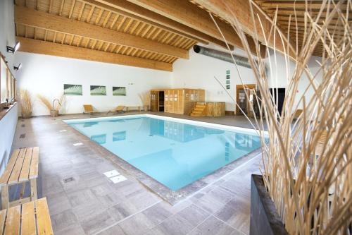 - une grande piscine dans une grande pièce dotée de plafonds en bois dans l'établissement Hameau 2 006 - SPA & PISCINE appartement 6 pers, à Orelle