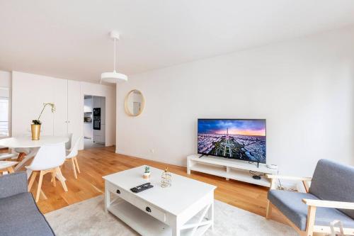 3 bedroom flat close Montmartre في باريس: غرفة معيشة مع تلفزيون كبير على جدار أبيض