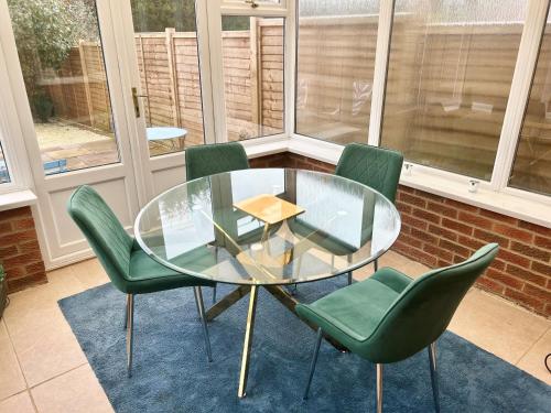 uma mesa de vidro e quatro cadeiras verdes num quarto em KB51 Charming 2 bed house in Horsham, pets very welcome and long stays with easy access to London, Brighton and Gatwick em Warnham