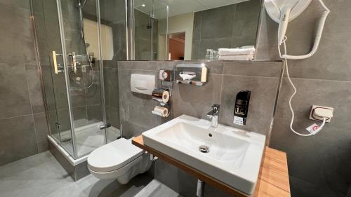 a bathroom with a sink and a shower and a toilet at Hotel Gute Hoffnung Pforzheim in Pforzheim
