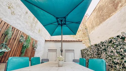 una mesa con sillas azules y una sombrilla azul en Almada Apartments 468, en Oporto