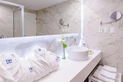 La salle de bains est pourvue d'un lavabo et de serviettes sur un comptoir. dans l'établissement NH San Luis Potosí, à San Luis Potosí