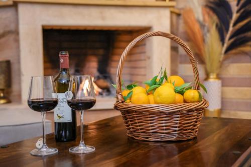 a basket of fruit and two glasses of wine at Archontiko Frideriki Luxury Apartments in Chios