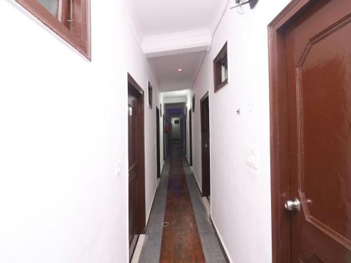 um corredor com paredes brancas e uma porta de madeira em OYO Hotel Chandrabhaga em Rishikesh