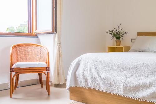 a bedroom with a bed and a chair next to a window at Starhost - La Casella seaview garden terrace and parking in Cetara