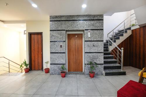 a hallway with a door and stairs with potted plants at Hotel HC Dream Majestic in Mohali