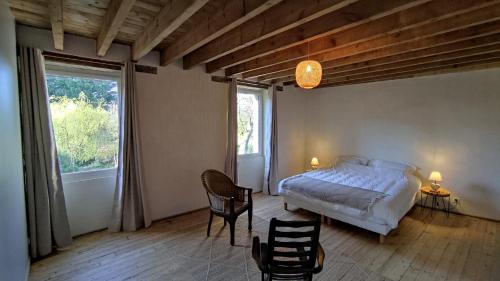ein Schlafzimmer mit einem Bett und einem großen Fenster in der Unterkunft Chambre d'hôte en Gîte - Moulin de la Houssaie - Brocéliande in Guer