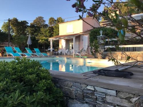 une piscine avec des chaises bleues et une maison dans l'établissement CORSE VILLA CARPE DIEM VUE MER 6 PERS PISCINE, à Santa-Maria-Poggio