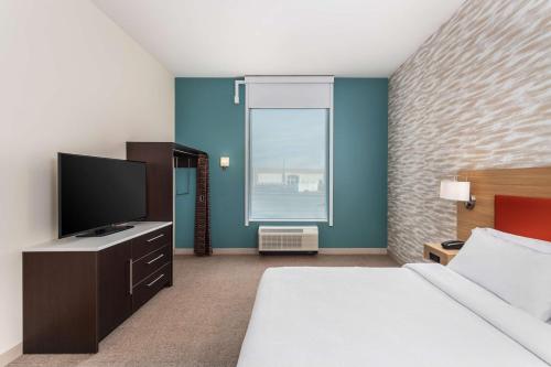 a hotel room with a bed and a flat screen tv at Home2 Suites By Hilton Cedar Rapids Westdale in Cedar Rapids