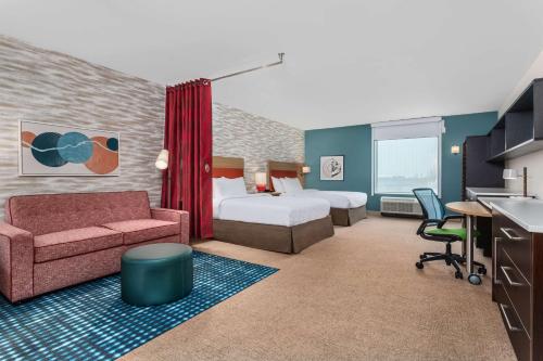 Habitación de hotel con dormitorio con cama y sofá en Home2 Suites By Hilton Cedar Rapids Westdale, en Cedar Rapids