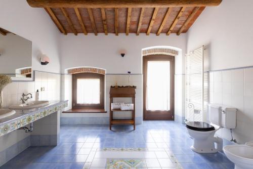 a bathroom with two sinks a toilet and two windows at VerdeOlivo 1876 - Apartments & Pool in Mezzane di Sotto