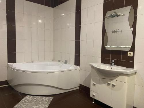 a bathroom with a tub and a sink at Viktoria Hotel in Obroshino