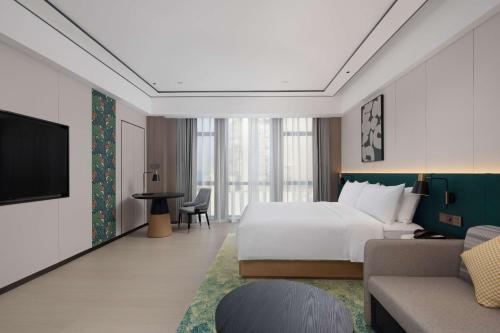 a hotel room with a bed and a tv at Hilton Garden Inn Jiangmen Xinhui in Jiangmen
