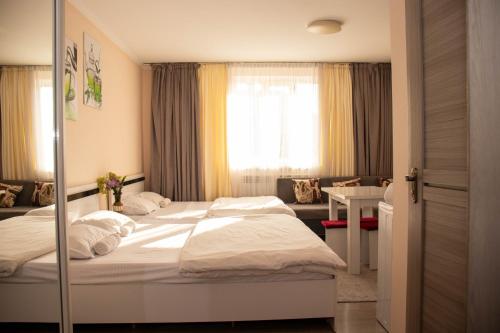 a bedroom with two beds and a desk and a window at A&G APART-HOTEL in Almaty