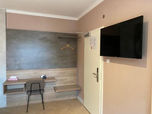 Habitación con escritorio y TV en la pared. en Hotel Petite Königsallee SELF CHECK-IN en Düsseldorf
