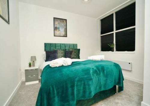 a white bedroom with a emerald green bed in it at The Bayard Plaza in Peterborough